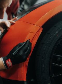 a man is working on an orange car